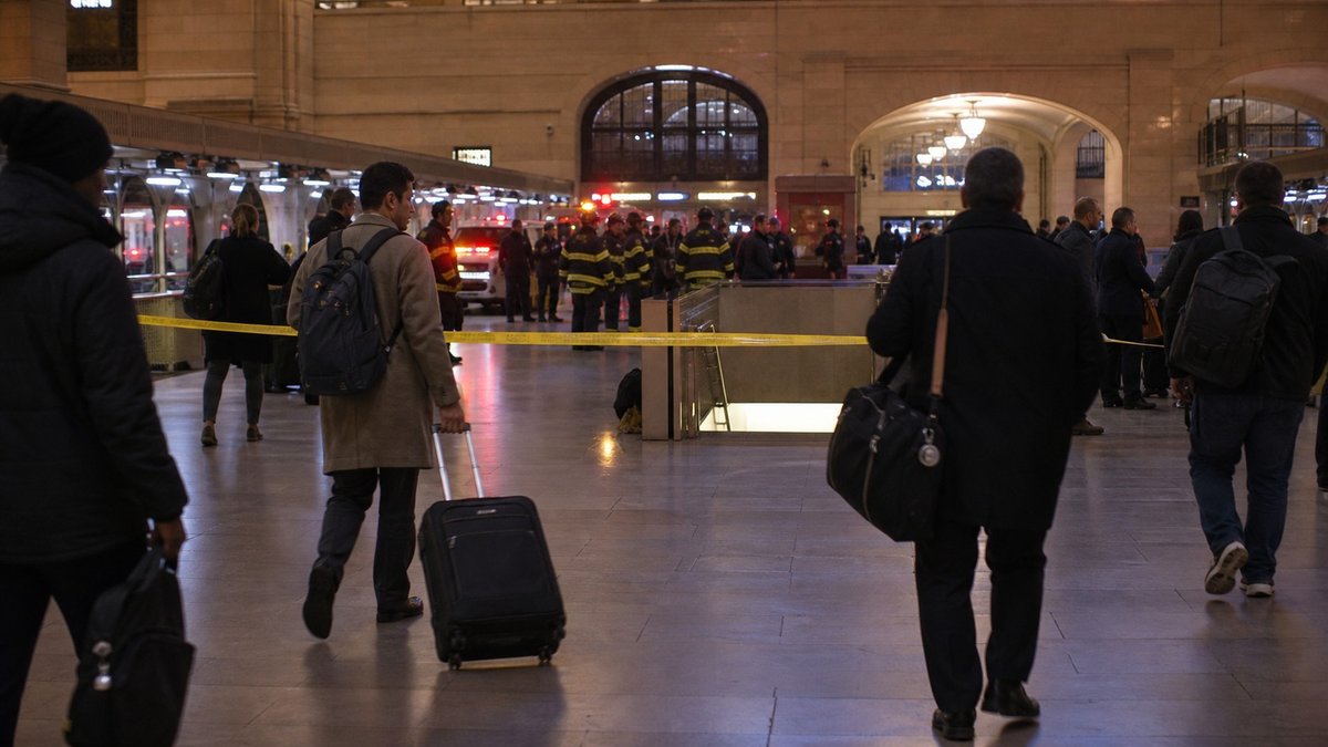 Área isolada por policiais em estação movimentada de Nova York à noite.