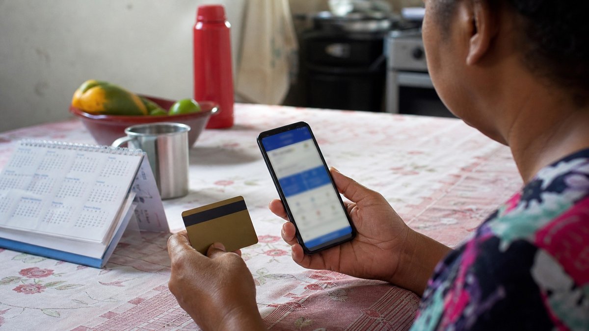 Celular com aplicativo bancario generico ao lado de calendario e documentos sobre uma mesa simples.