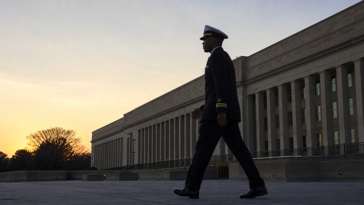 Exterior do Pentágono com silhueta de oficial da Marinha dos Estados Unidos caminhando ao amanhecer