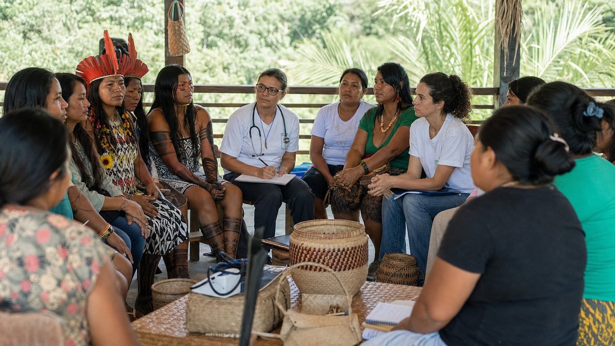 Parteiras indígenas e profissionais de saúde reunidos em roda de conversa sobre cuidado materno.