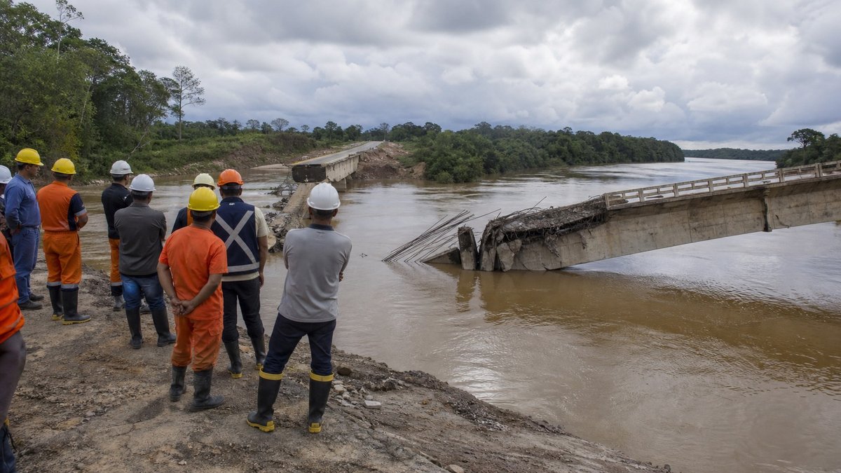 Ponte de concreto desabada sobre rio amazônico com equipes de emergência observando a área.